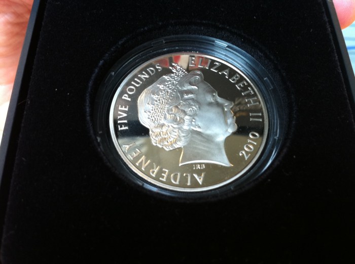 O verso da moeda - "God Save the Queen". Aos curiosos, "Alderney" é a ilha que está mais ao norte do conglomerado conhecido como "Channel Islands", da coroa britânica. A população local é de 2.400 habitantes (Wikipedia)