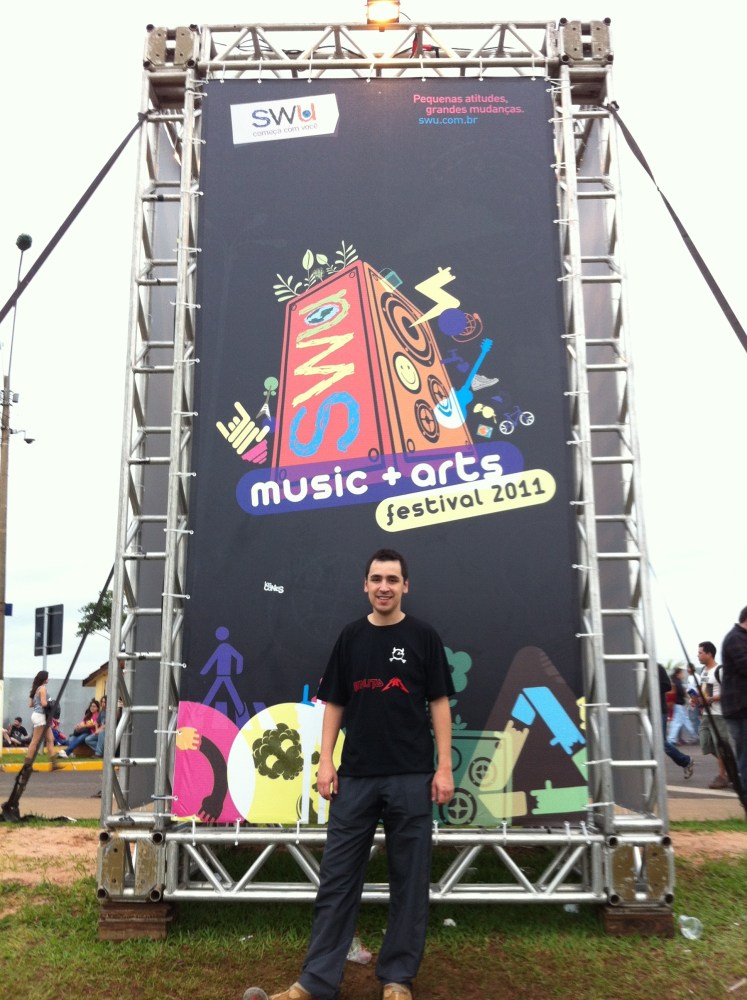 Eduardo na placa que indicava a localização dos palcos, alimentação, banheiros, etc.